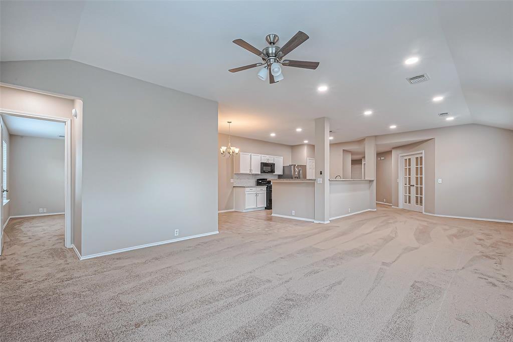 a view of a livingroom with a ceiling fan & kitchen view