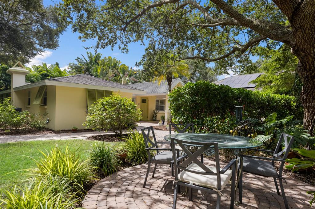 a backyard of a house with table and chairs under an umbrella