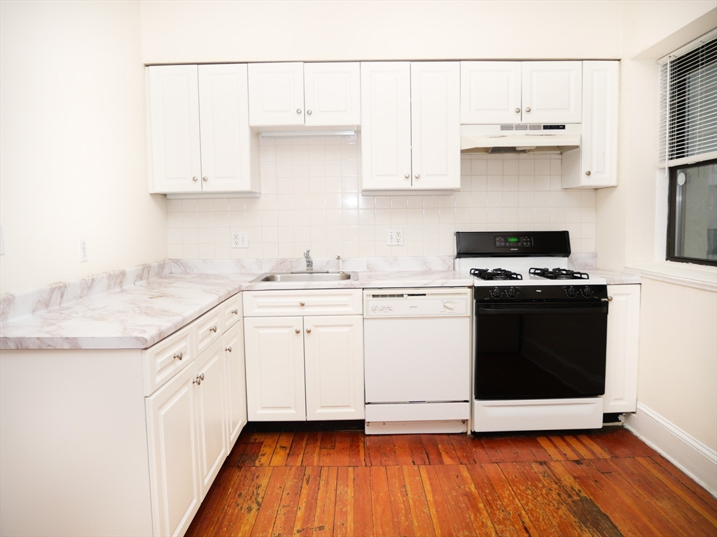 a kitchen with granite countertop white cabinets and white appliances