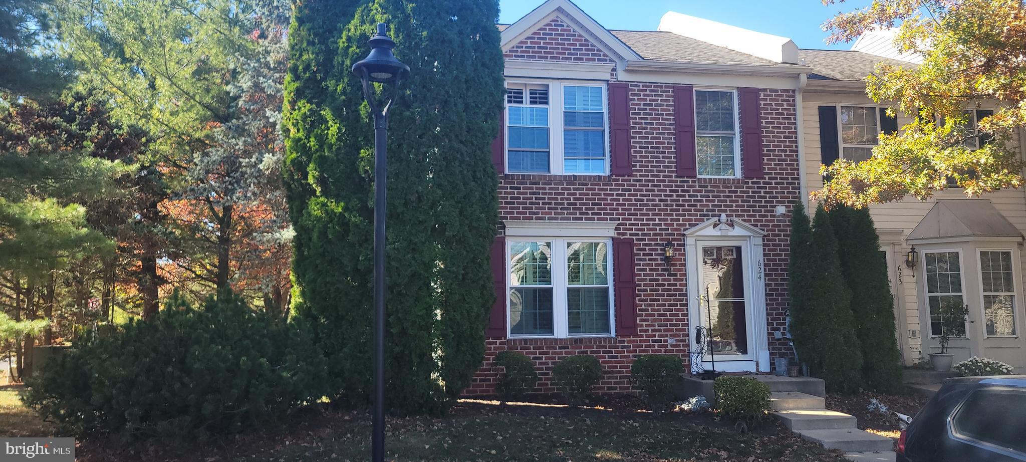 a view of a brick house with a yard and large tree