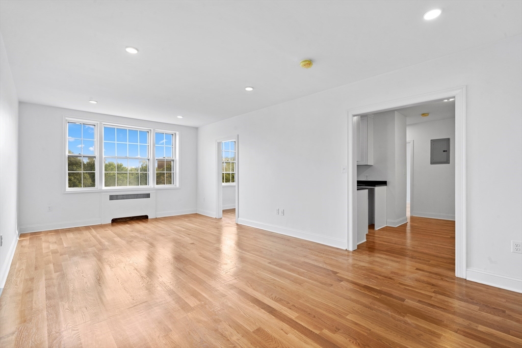 a view of an empty room with wooden floor and windows