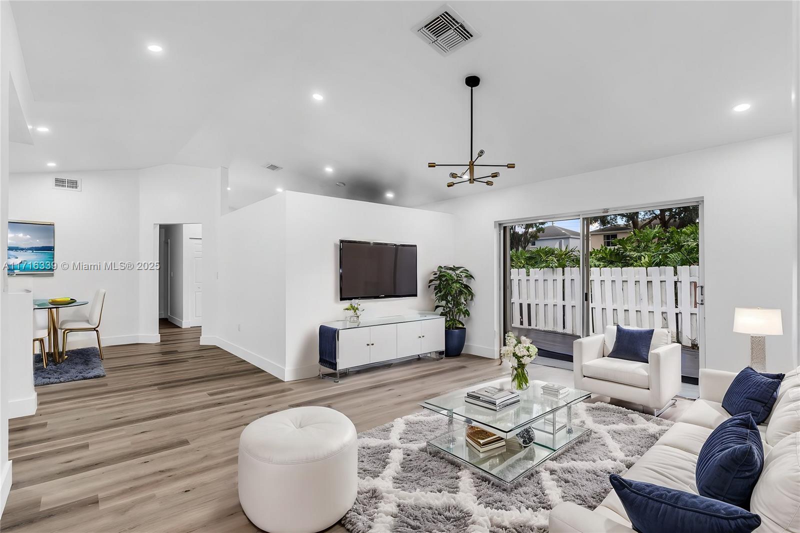 a living room with furniture a flat screen tv and a floor to ceiling window