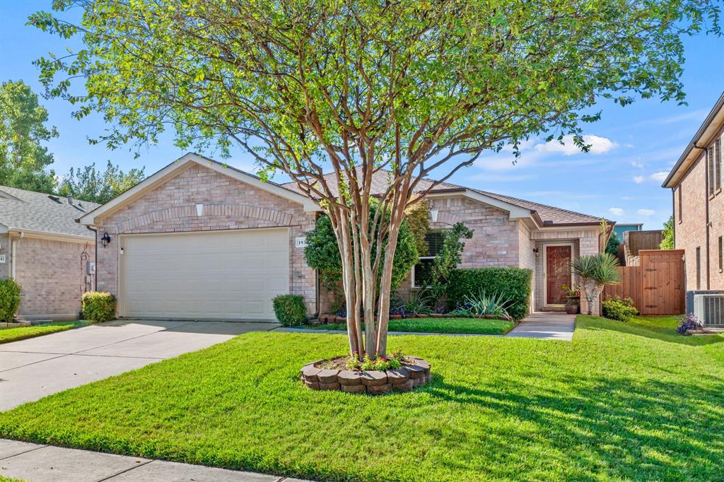 a front view of a house with a yard and tree