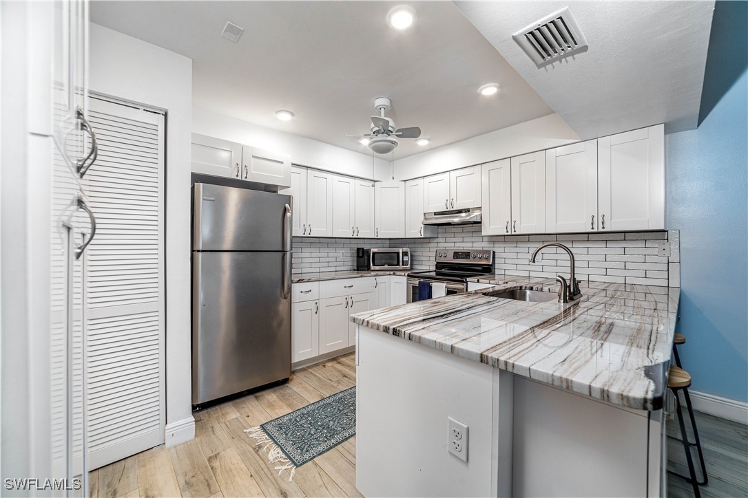 a kitchen with refrigerator a microwave a sink and cabinets