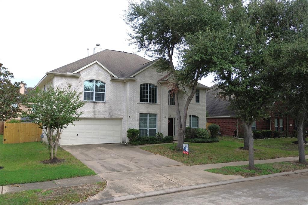 a front view of a house with a garden and trees