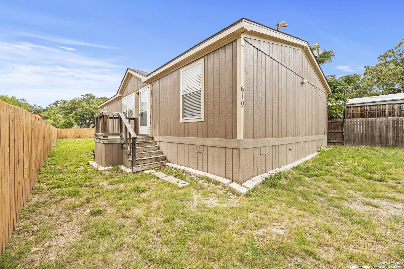 a view of backyard of house with wooden fence