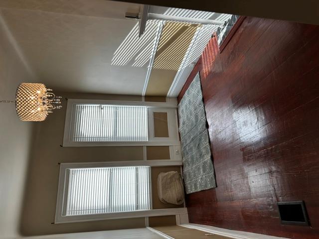 Doorway to outside featuring a chandelier, a wealth of natural light, and dark wood-type flooring