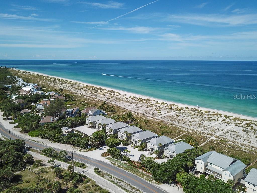 an aerial view of ocean and residential houses with outdoor space