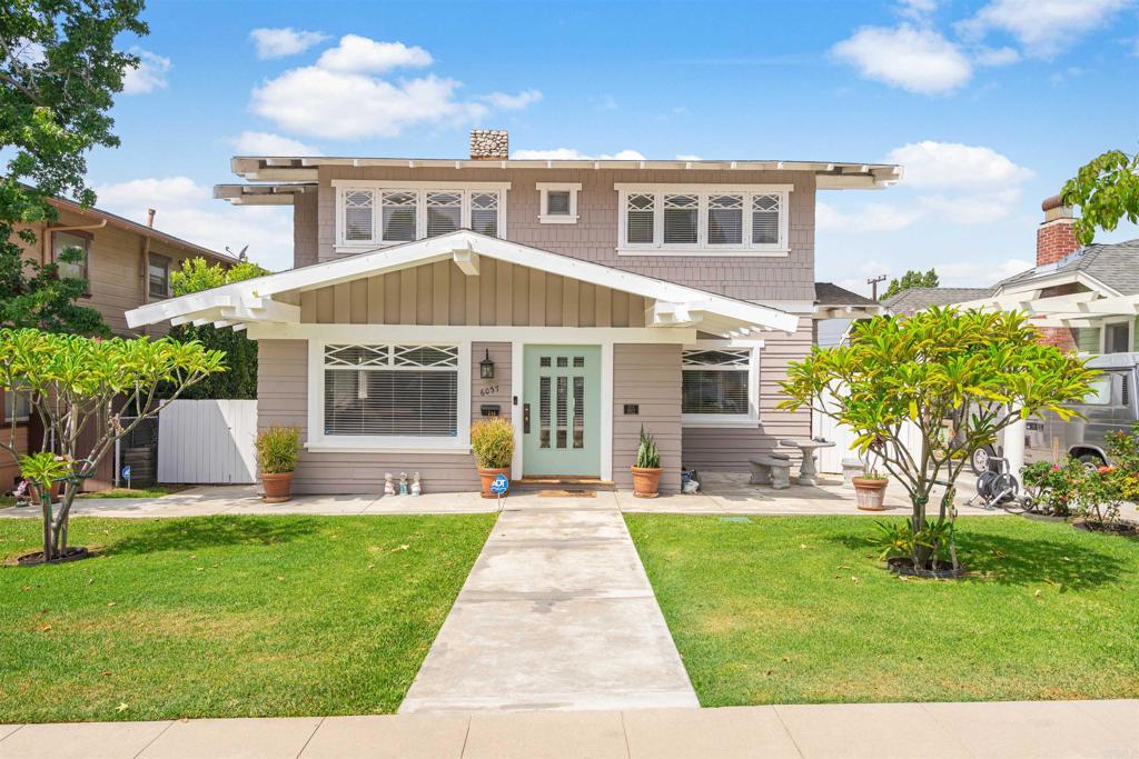 a front view of a house with a yard and potted plants