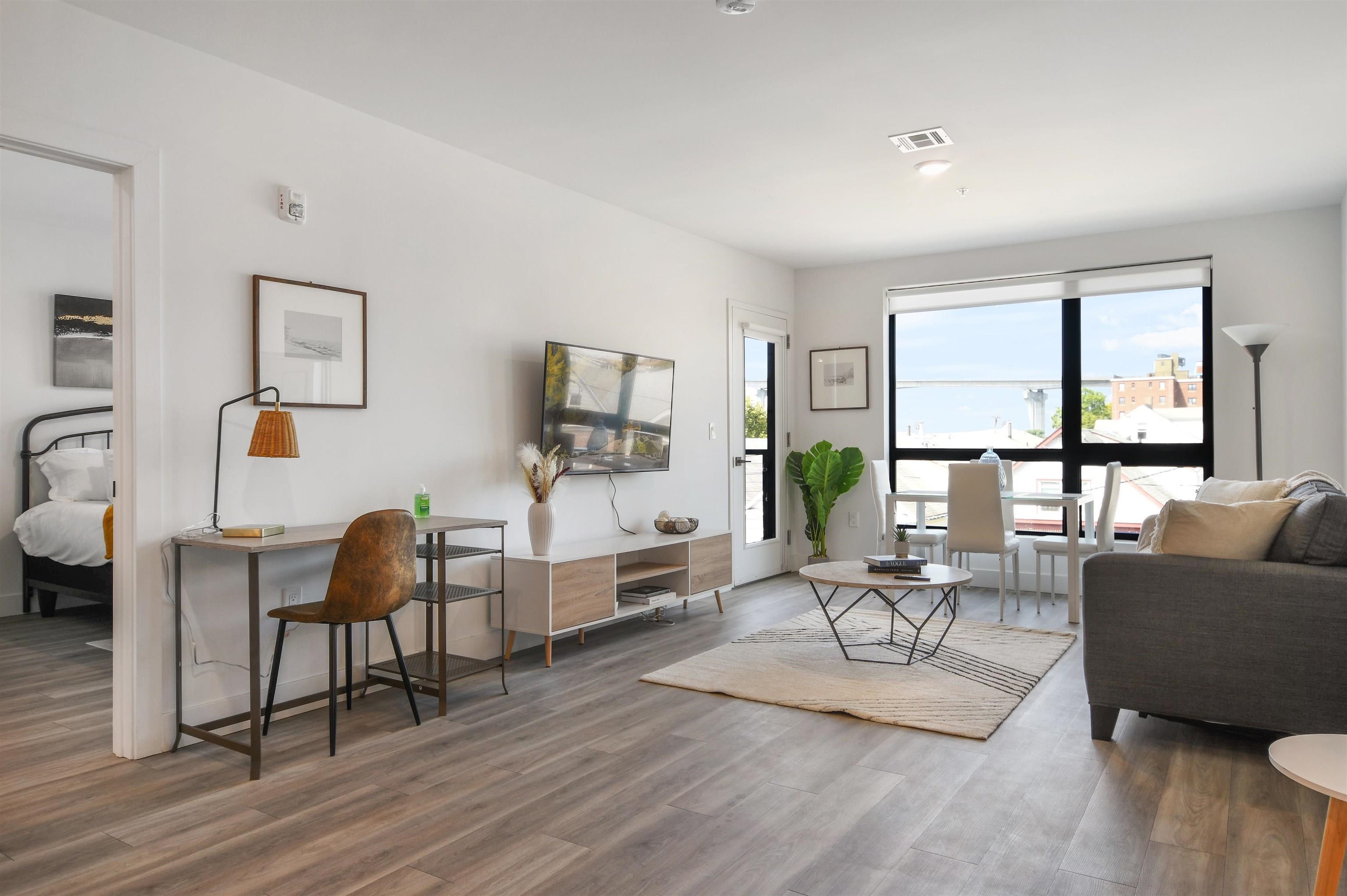 a living room with furniture a flat screen tv and a floor to ceiling window