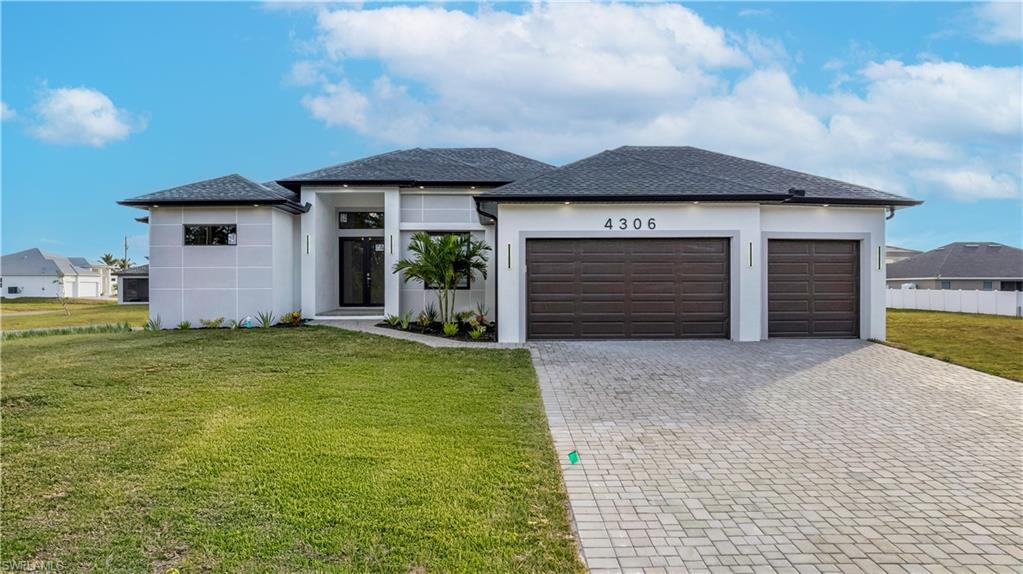 View of front facade featuring a front yard and a garage