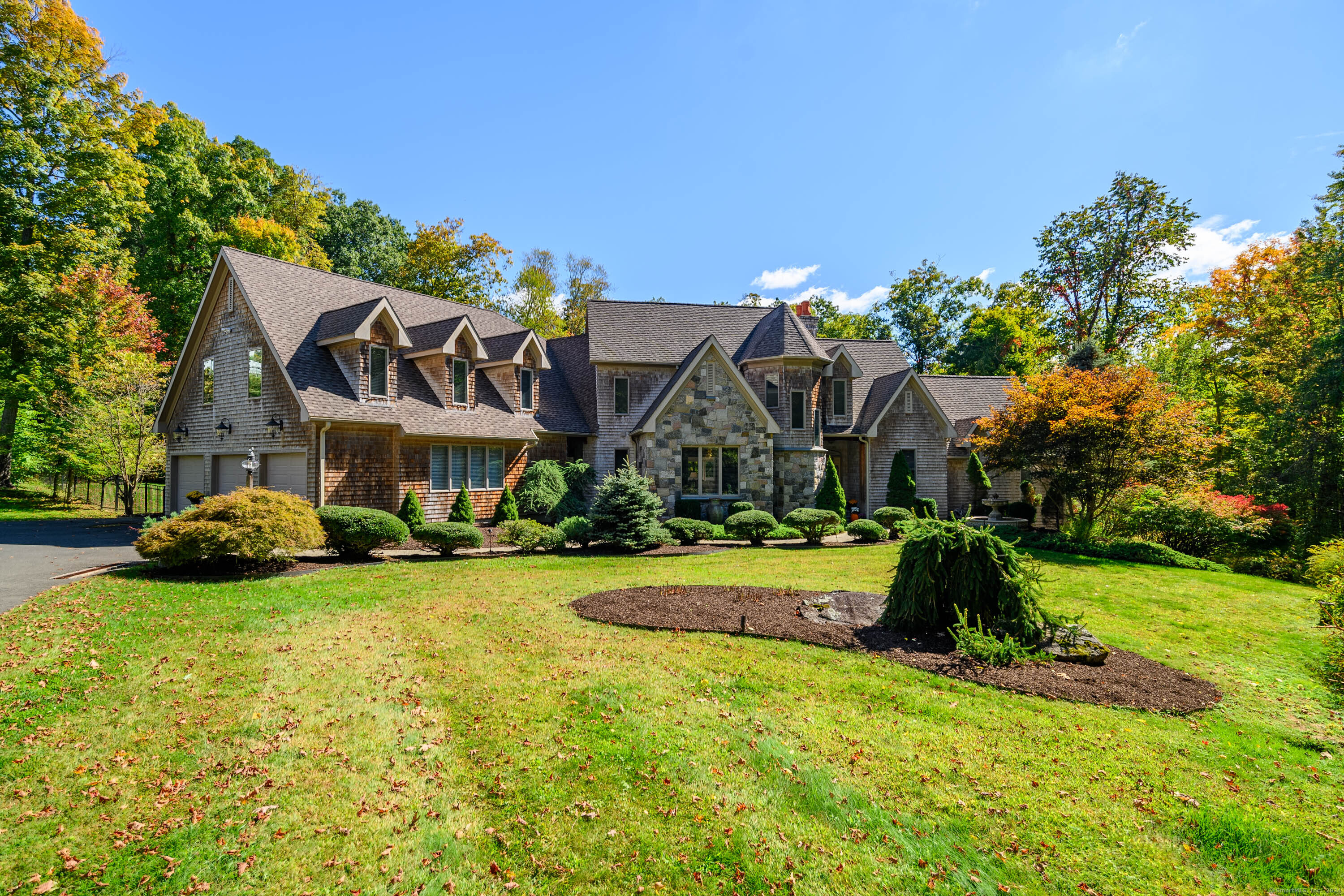 a front view of a house with a garden and a tree