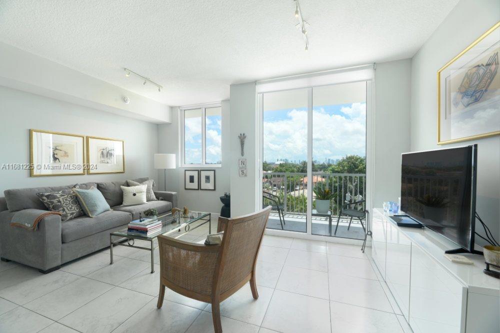 a living room with furniture a flat screen tv and a floor to ceiling window