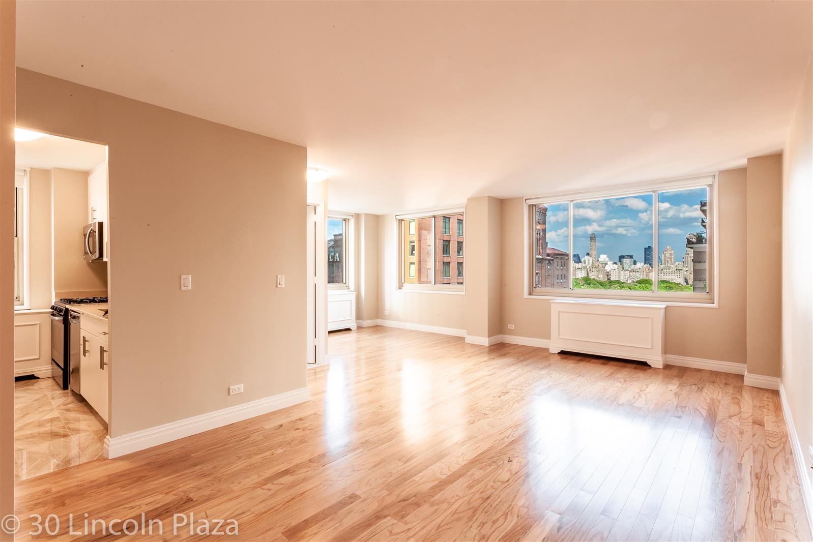 a view of an empty room with a window and wooden floor