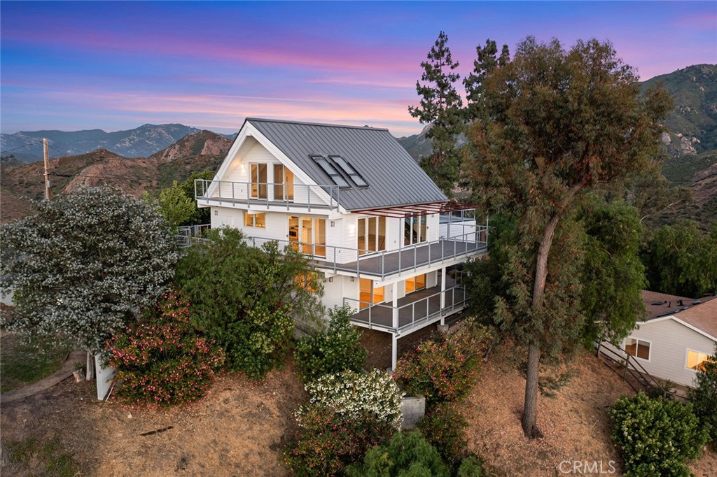 a front view of a house with a yard and mountain view in back