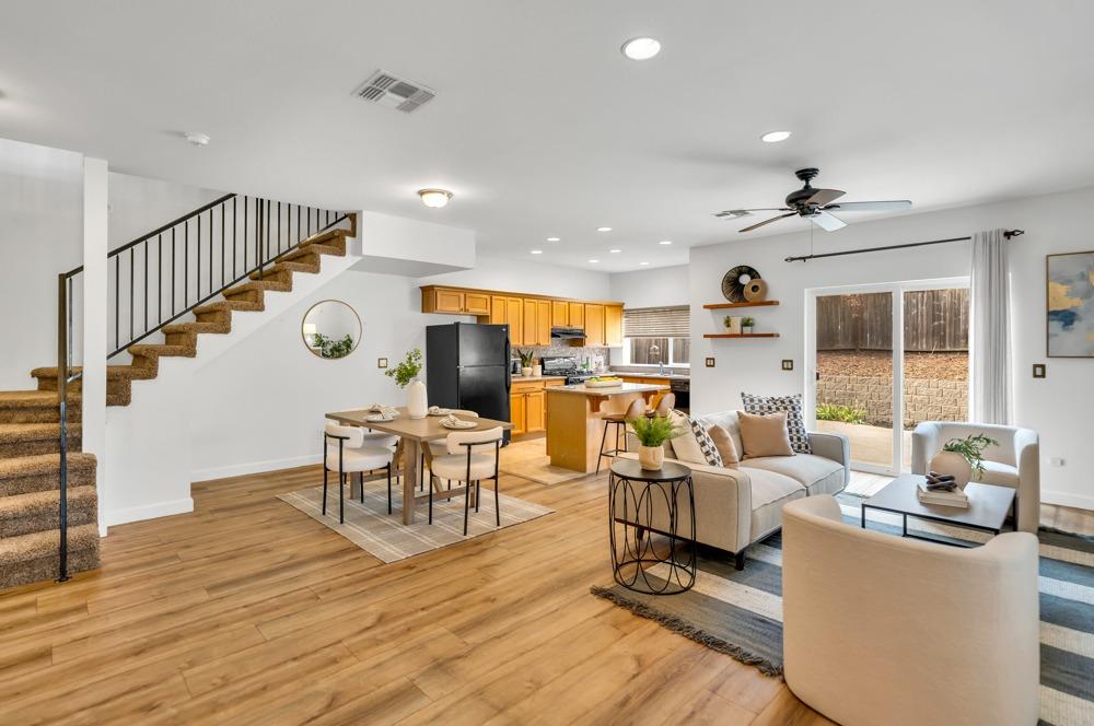 a living room with furniture kitchen view and a wooden floor