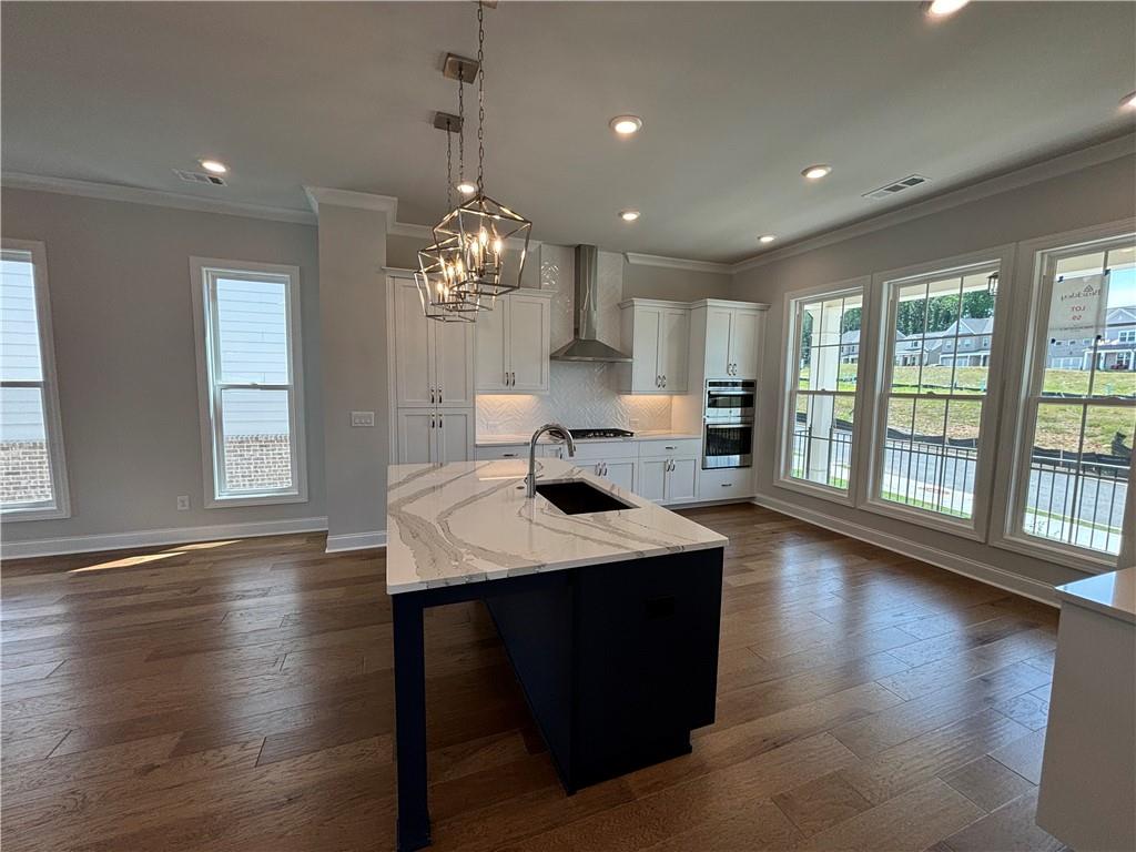 a open kitchen with dining table a chandelier and wooden floor