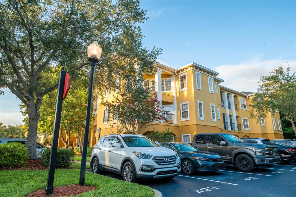 a front view of a residential apartment building with a yard and parking space