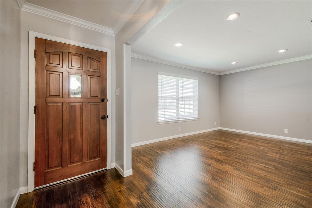 an empty room with wooden floor cabinet and windows