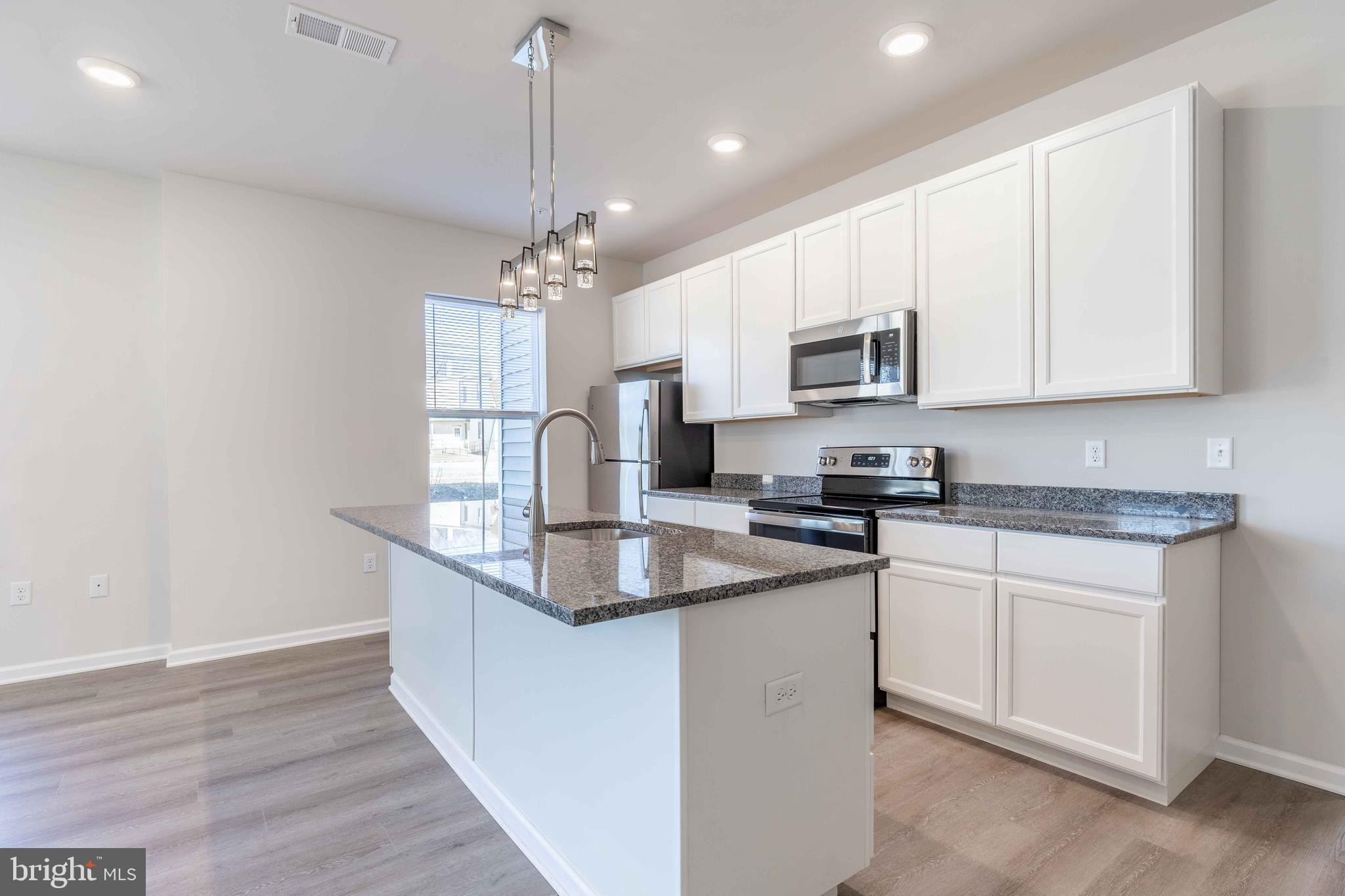 a kitchen with kitchen island granite countertop a sink a counter space stainless steel appliances and cabinets