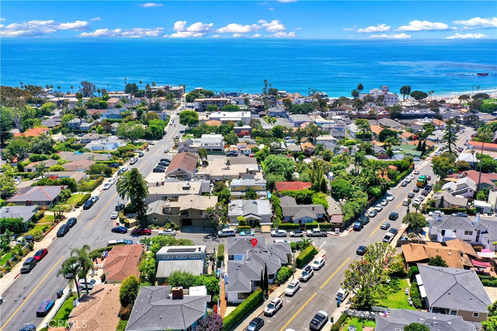 an aerial view of a city with lots of residential buildings and ocean view in back