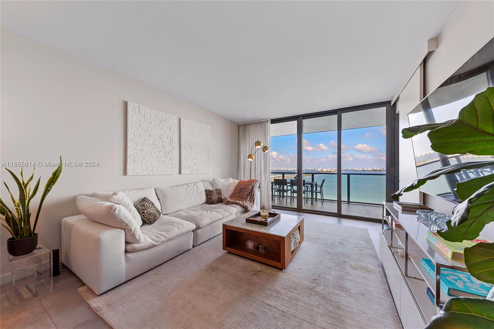 a living room with furniture a flat screen tv and a floor to ceiling window