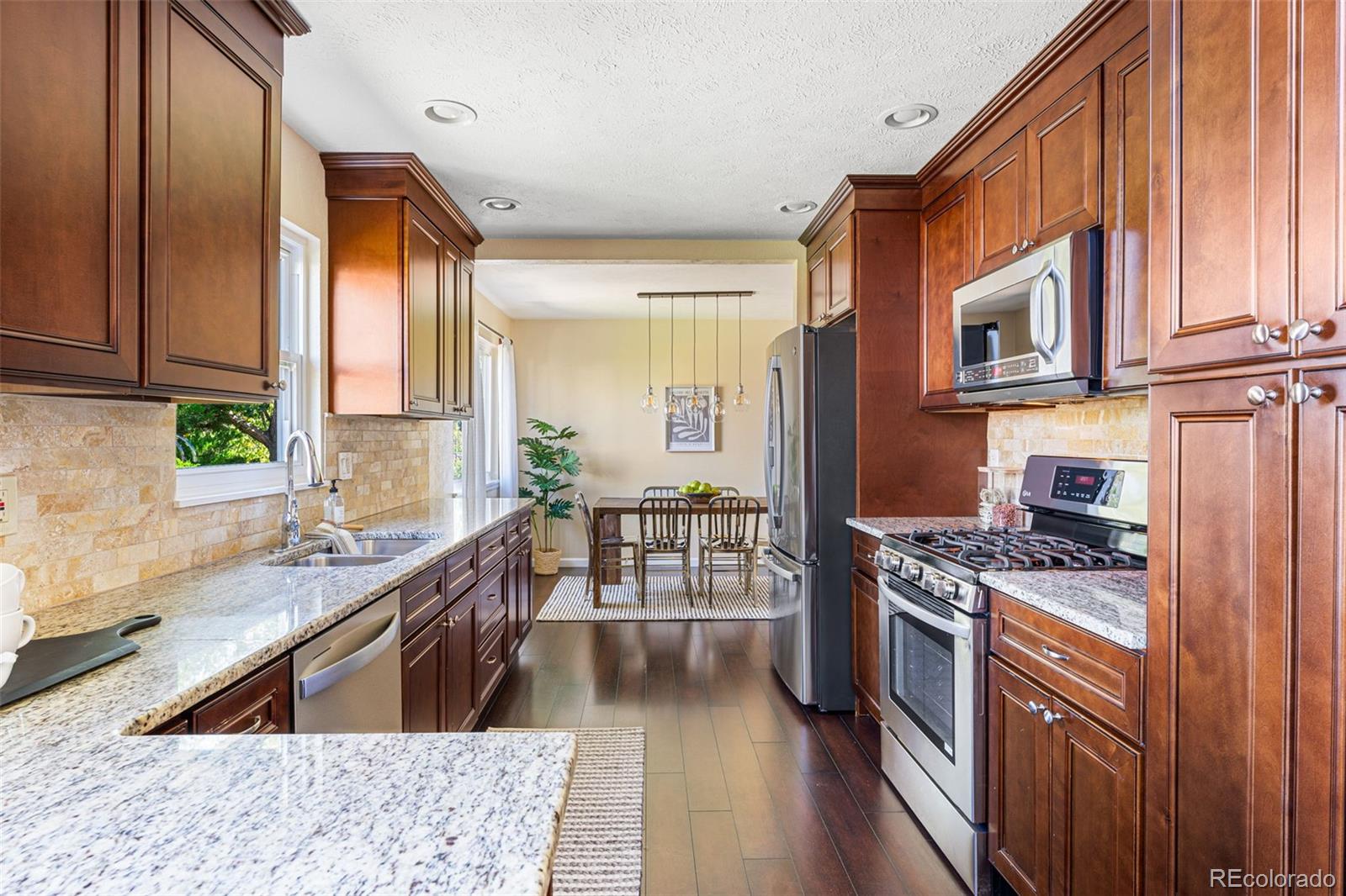 a kitchen with stainless steel appliances granite countertop a stove a sink and a microwave