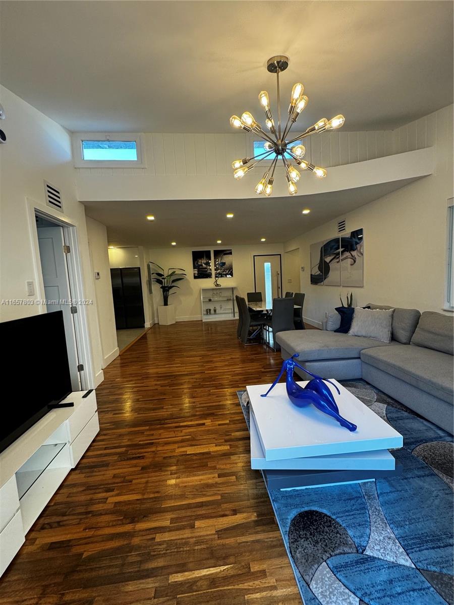 a living room with furniture a flat screen tv and kitchen view