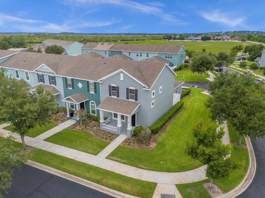 an aerial view of residential houses with outdoor space and trees