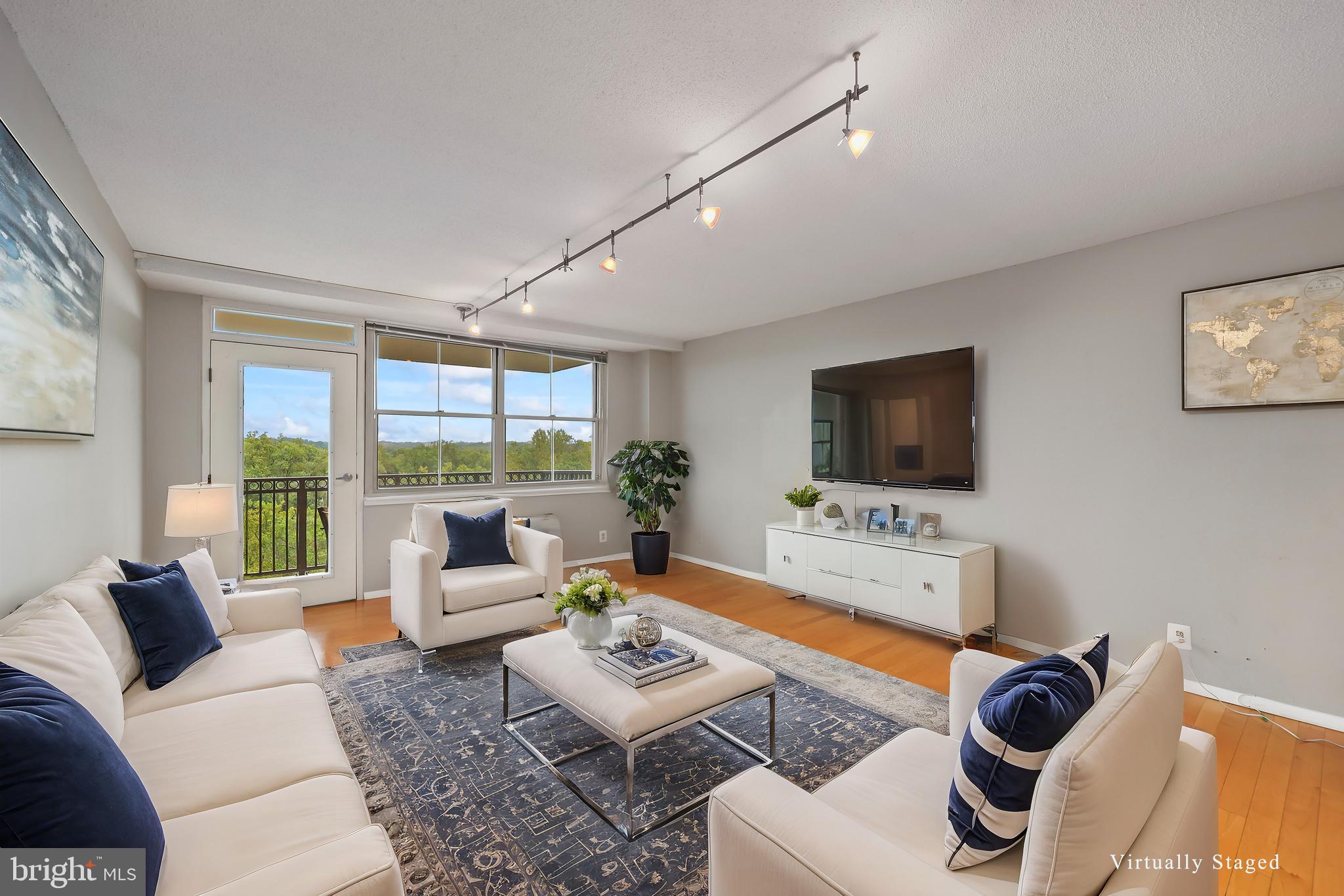 a living room with furniture a flat screen tv and a floor to ceiling window