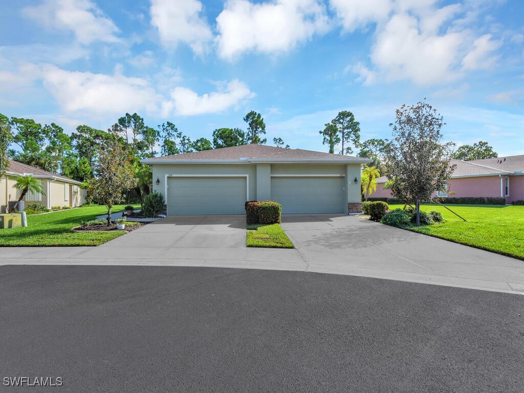 a view of a house with a small yard and a large parking space