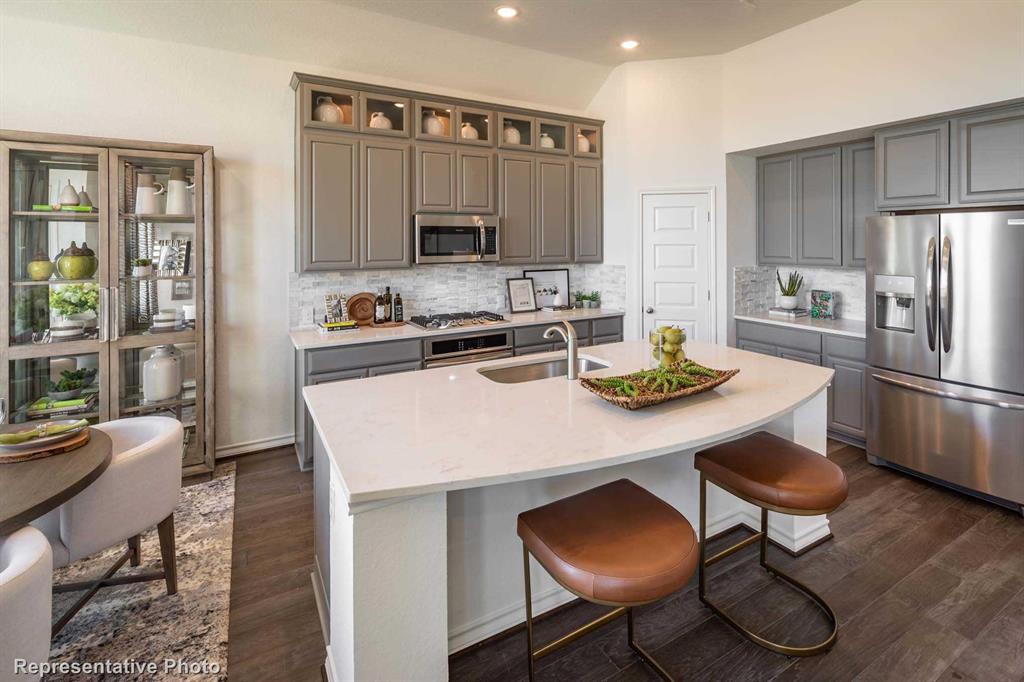 a kitchen with stainless steel appliances a dining table chairs and refrigerator