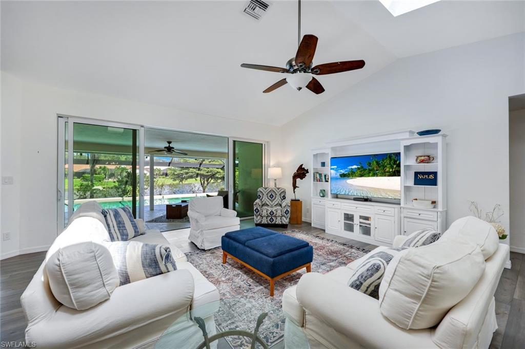 Living room with dark hardwood / wood-style flooring, ceiling fan, and high vaulted ceiling