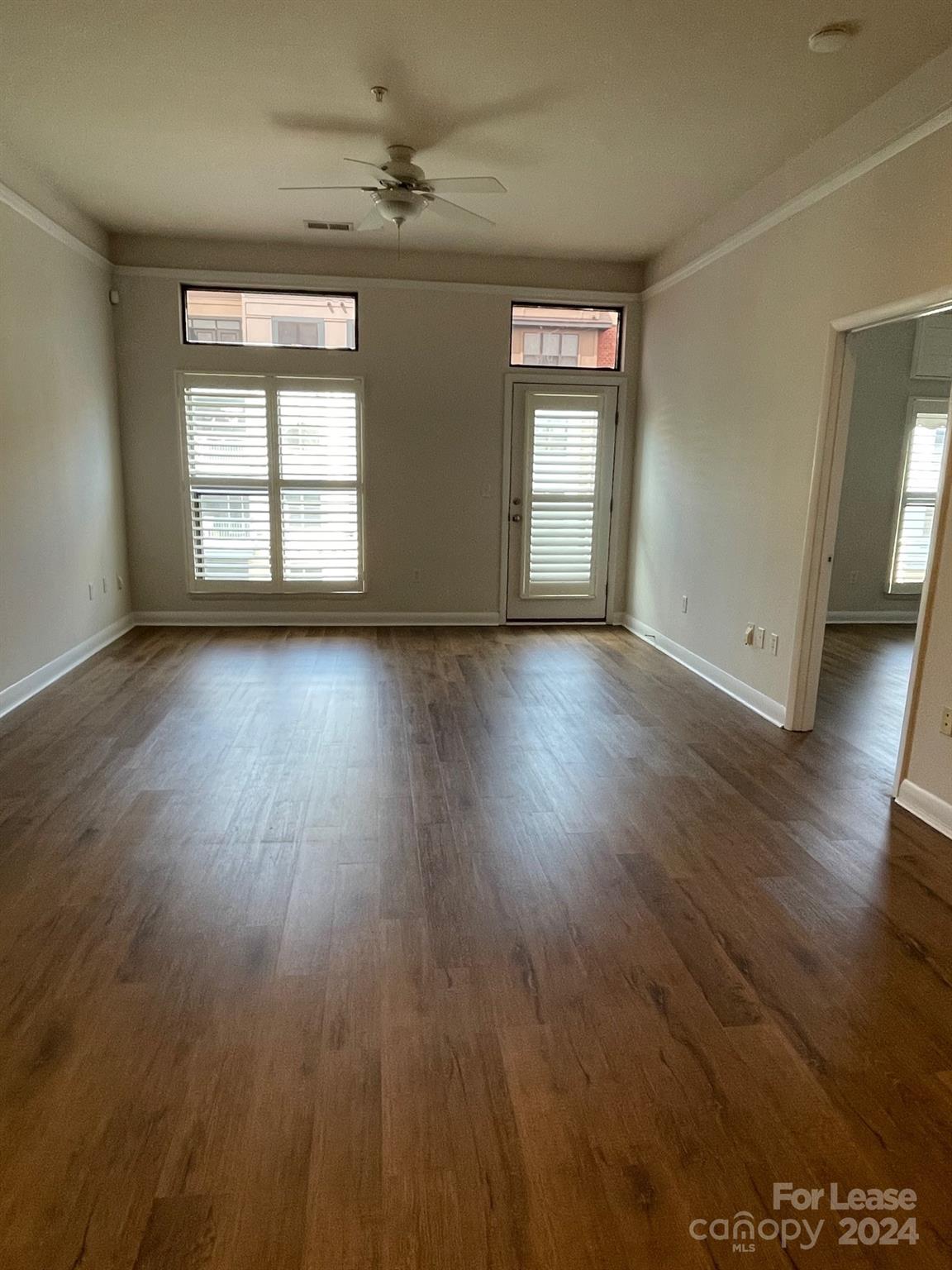 an empty room with wooden floor and windows