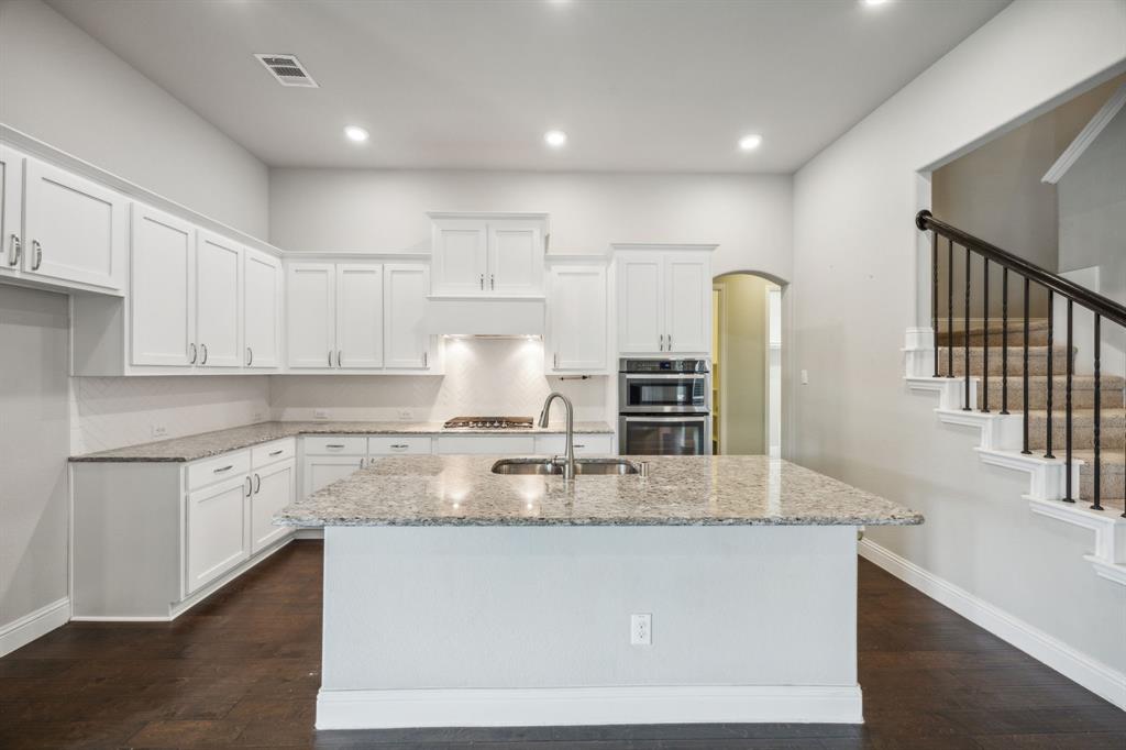 a kitchen with kitchen island granite countertop a stove and a sink