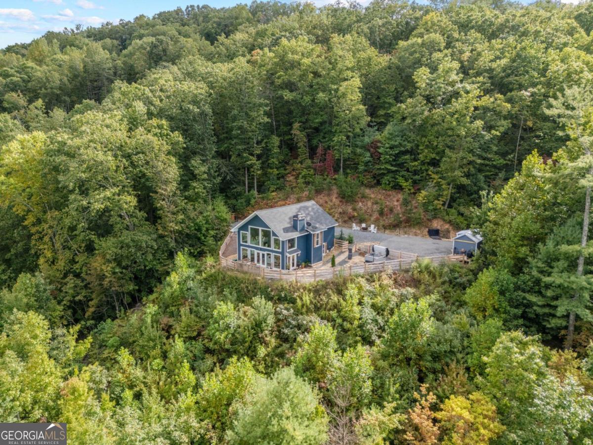 an aerial view of a house with yard and trees in the background