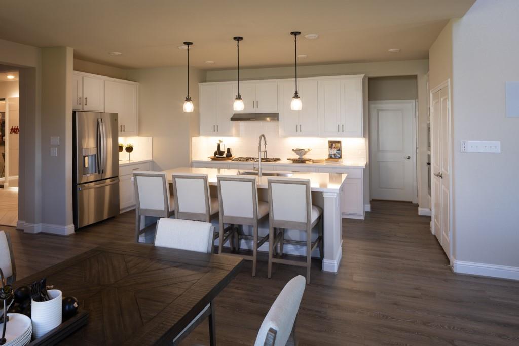 a kitchen with stainless steel appliances a dining table chairs stove and refrigerator