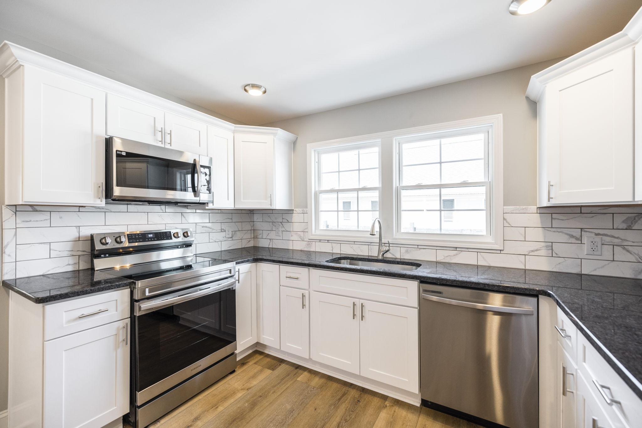 a kitchen with granite countertop white cabinets and stainless steel appliances