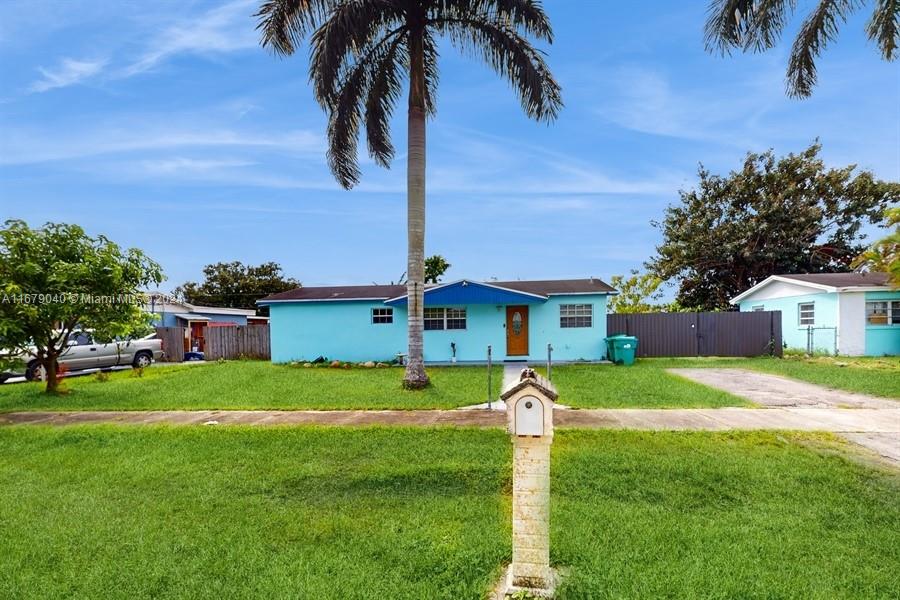 a view of a house with a big yard plants and palm trees