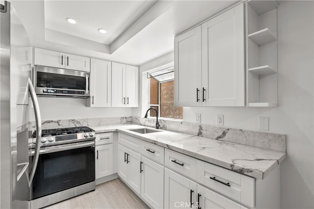 a kitchen with granite countertop a sink dishwasher stove and microwave with wooden cabinets