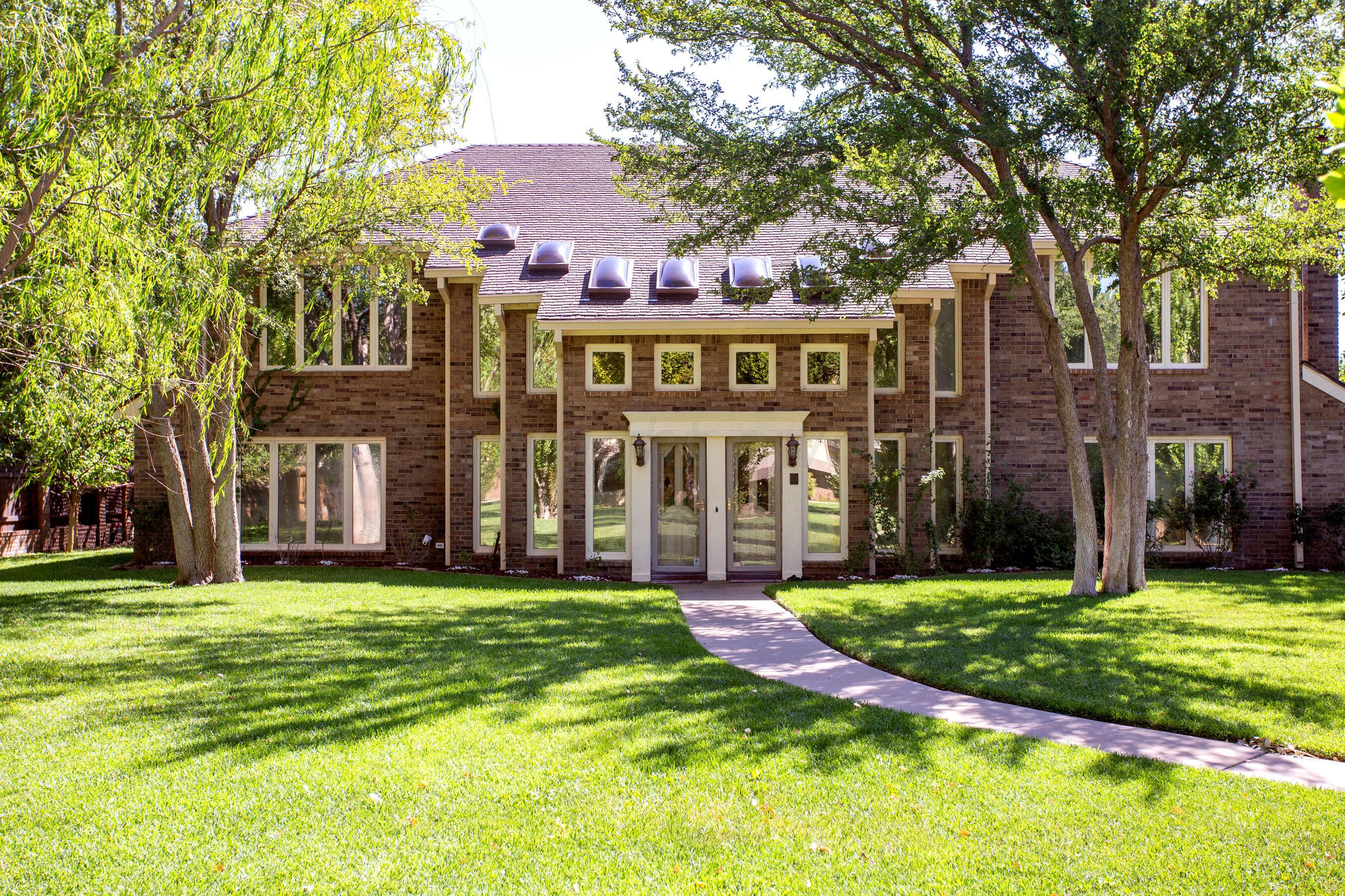 a view of a building with a big yard and large trees