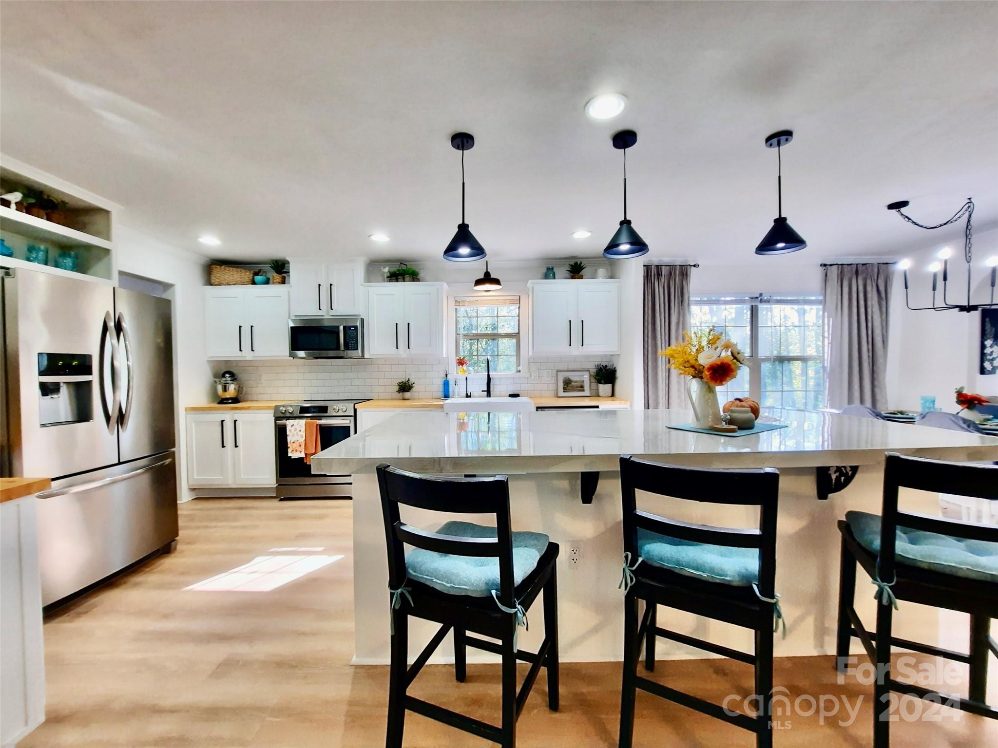 a kitchen with stainless steel appliances kitchen island granite countertop a table chairs in it and wooden floors