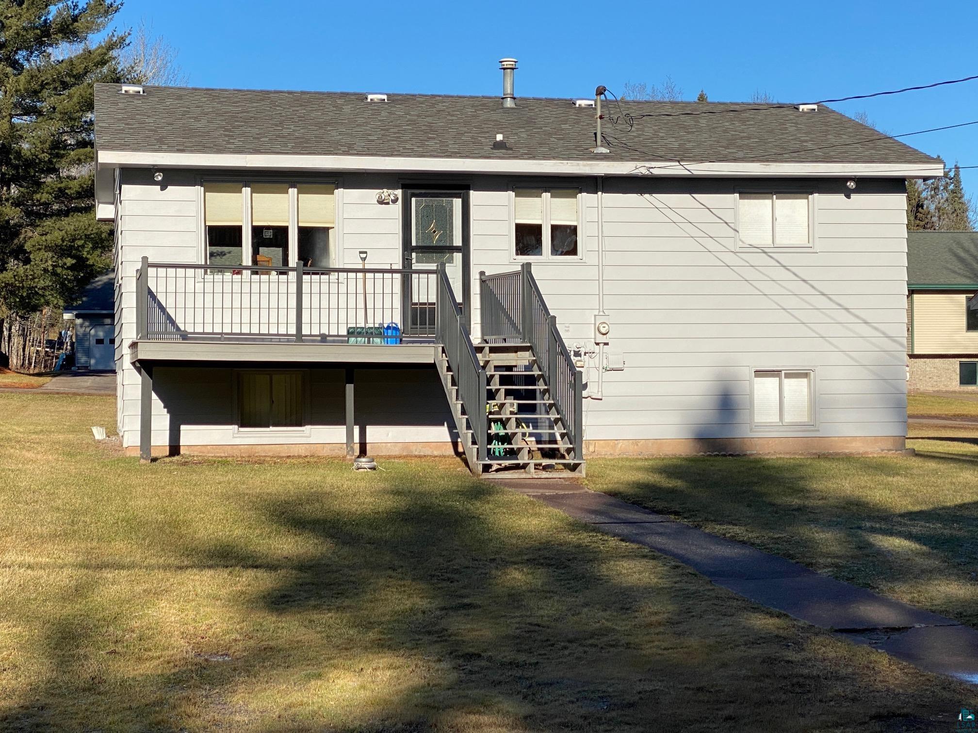 Rear view of property featuring a deck and a lawn