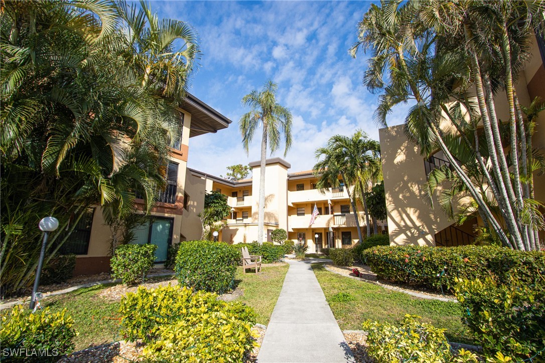 a front view of a multi story residential apartment building with yard and green space