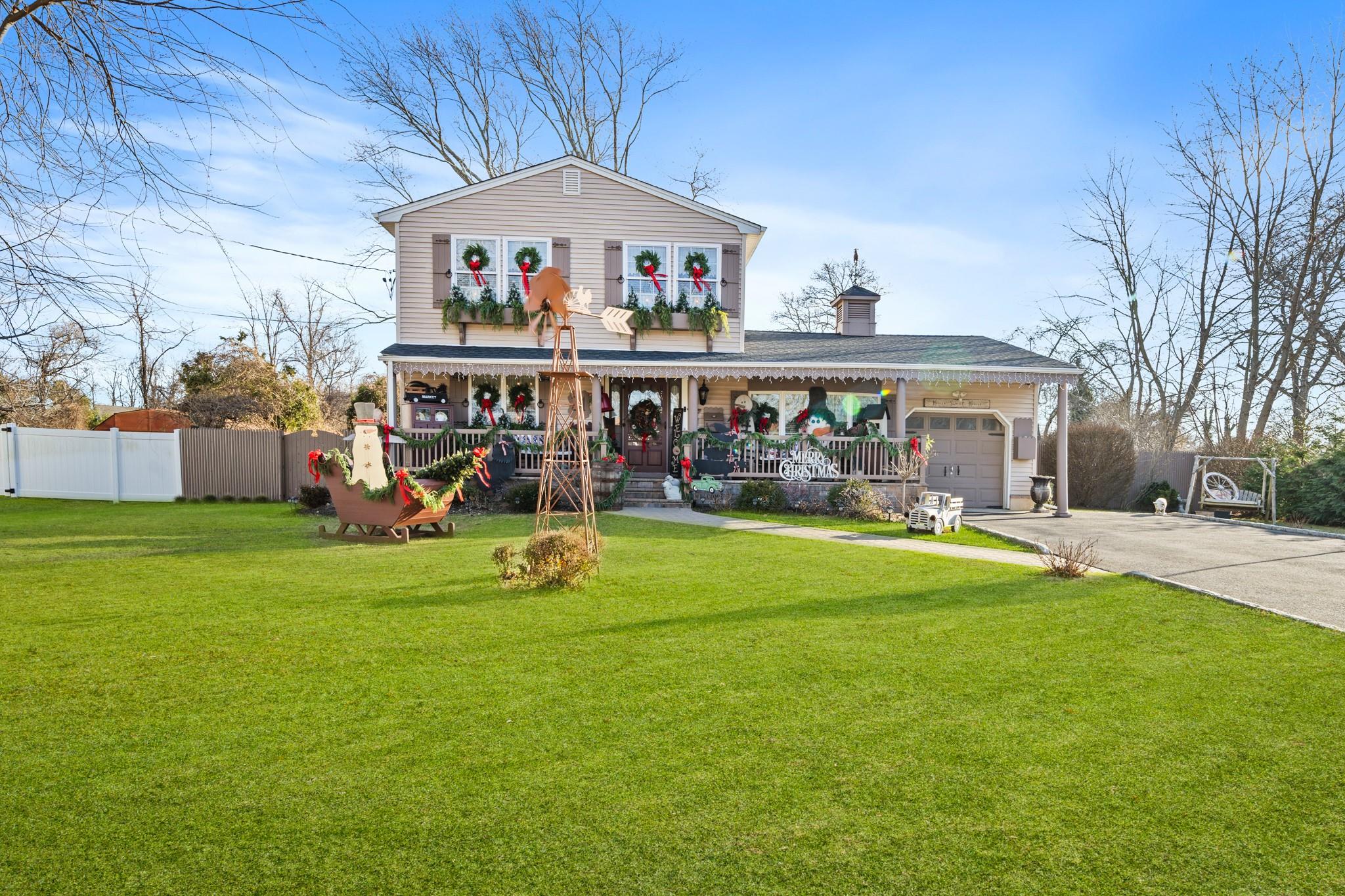 View of front of property with covered porch, expansive driveway and garage