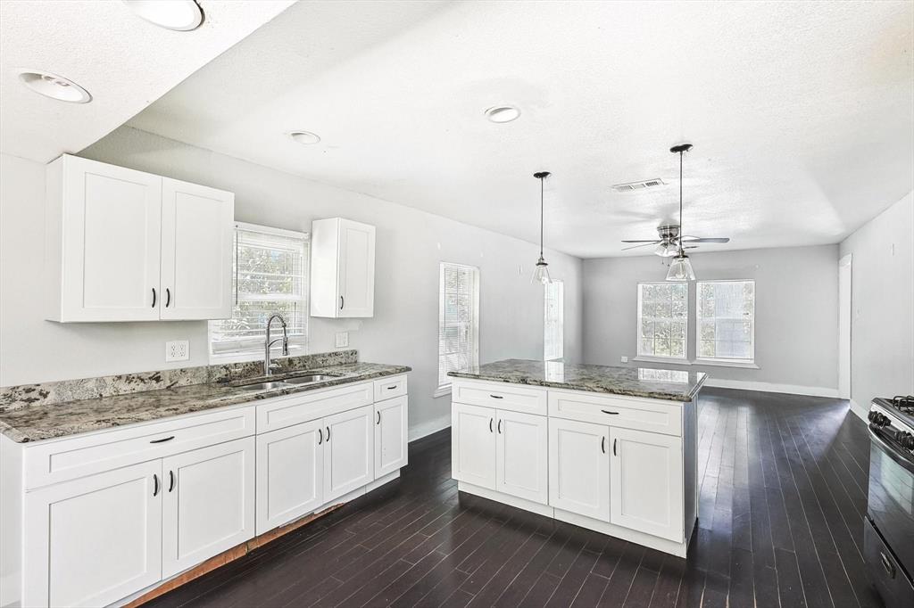 a kitchen with a sink dishwasher and white cabinets with wooden floor