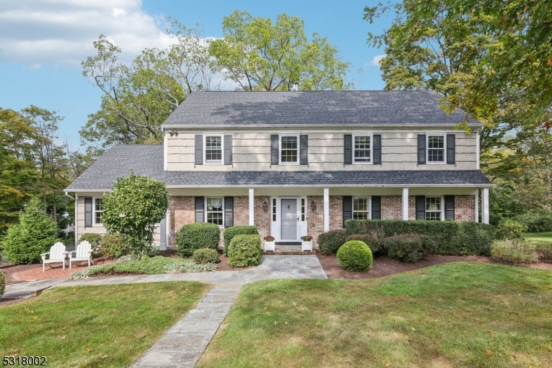 a view of a brick house with a big yard plants and large trees