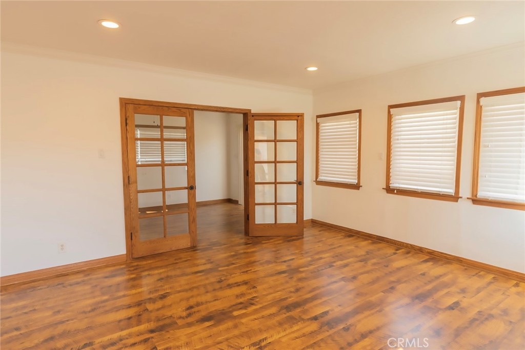 an empty room with wooden floor and windows