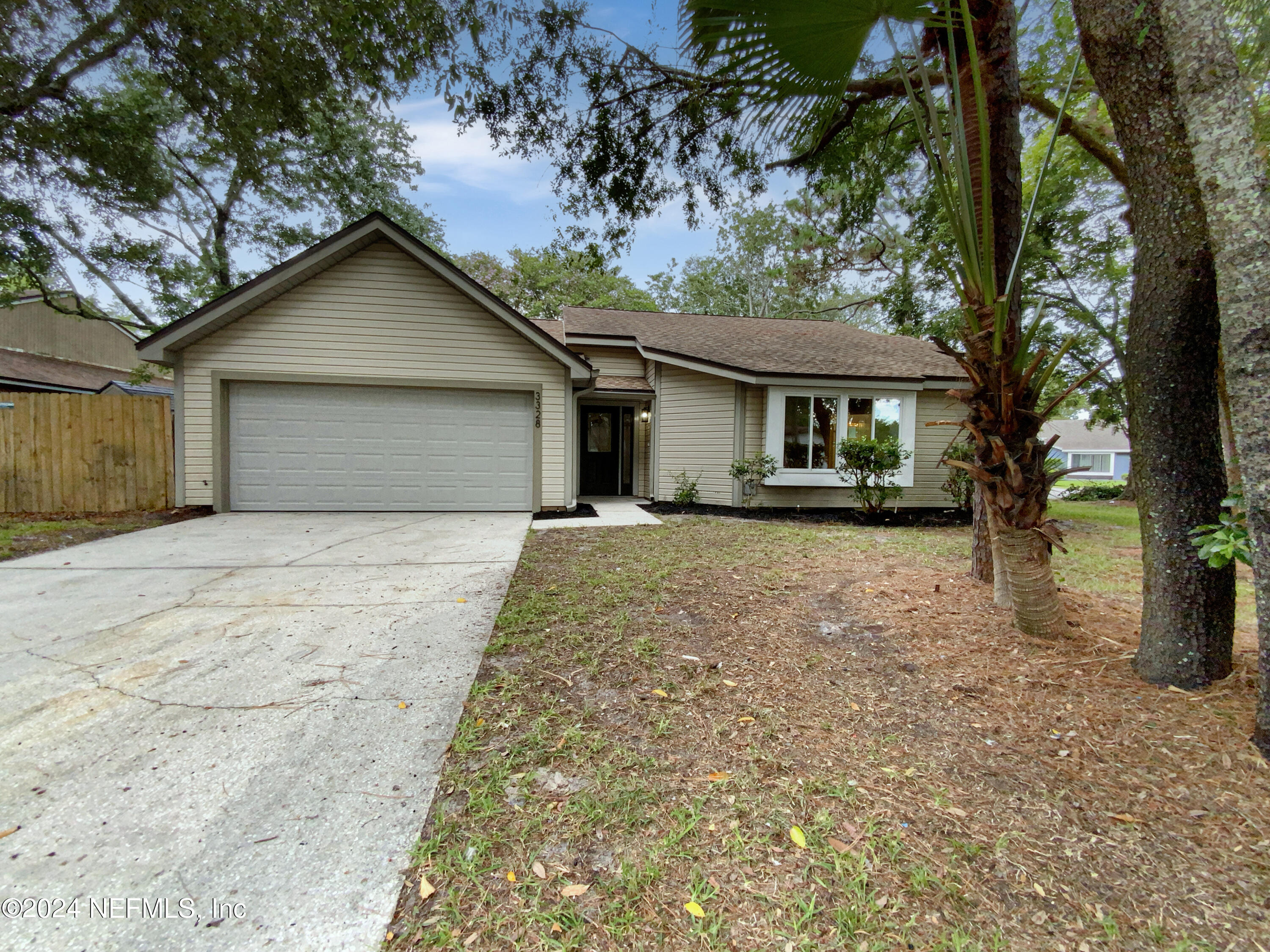 front view of house with a yard and trees all around