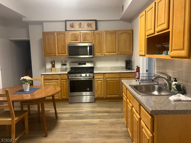 a kitchen with stainless steel appliances granite countertop a sink stove microwave and refrigerator